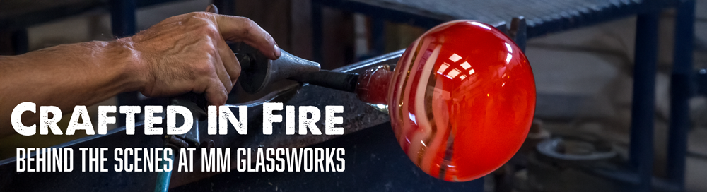 an artisan manually working on hand blown glass